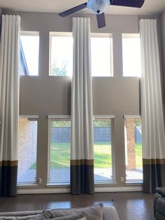 a living room with two windows and a ceiling fan in the middle of the room