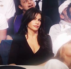 a woman sitting next to a man in a crowd at a tennis match with other people behind her