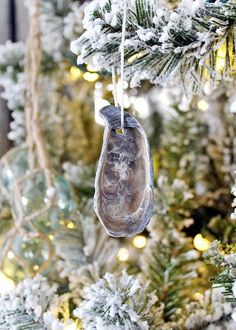 an ornament hanging from a christmas tree in front of snow - covered branches