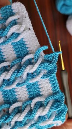 a crocheted blanket being worked on with a knitting needle