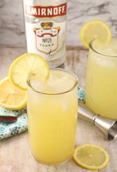 two glasses filled with lemonade next to a bottle