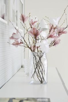 a vase filled with pink flowers sitting on top of a white counter next to a window