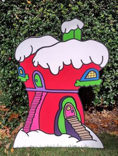 a cardboard house with snow on the roof and stairs in front of some shrubbery