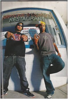 two men standing next to each other in front of a restaurant with their hands up