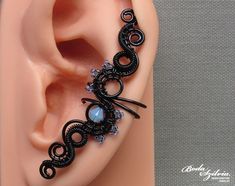 Handmade gothic crystal ear cuff, no piercing required. It's made of black artistic wire, tiny light blue seed beads and a beautiful pale blue swarovski crystal. It looks great on both the left or right ear. Made for order. I'll need 1-5 days to make your ear cuff. Please note that each one is made 100% by hand and may vary a little from the photo. You can find more ear cuffs here: https://www.etsy.com/shop/bodaszilvia?section_id=10952870&ref=shopsection_leftnav_2 Plz, read my policies before bu Bohemian Black Jewelry With Internally Threaded Details, Handmade Black Ear Cuff, Handmade Adjustable Black Ear Cuff, Handmade Adjustable Gothic Ear Cuff, Handmade Black Ear Cuff As Gift, Handmade Black Bohemian Body Jewelry, Handmade Black Ear Cuff For Gift, Handmade Black Ear Cuff Gift, Black Ear Cuff