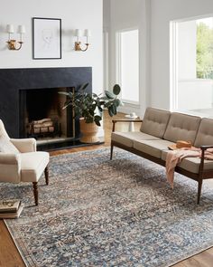 a living room filled with furniture and a fire place next to a large rug on top of a hard wood floor