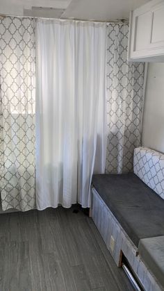 a small room with a bed and curtains in it