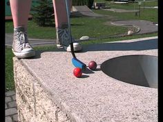 a person standing on the edge of a pool with two balls and a croquet