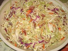 a white plate topped with coleslaw on top of a table next to a knife and fork