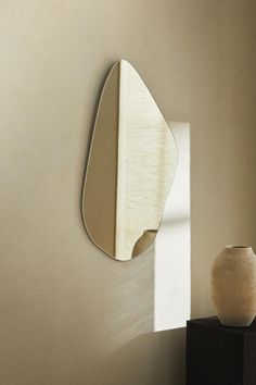 a vase sitting on top of a table next to a wall mounted mirror and light fixture