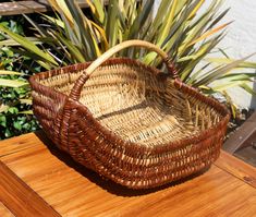 a wicker basket sitting on top of a wooden table next to a potted plant