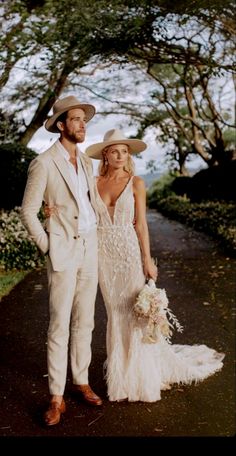 a man and woman in wedding attire standing next to each other on a path surrounded by trees