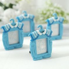 three small blue frames are sitting next to each other on a white table with flowers in the background