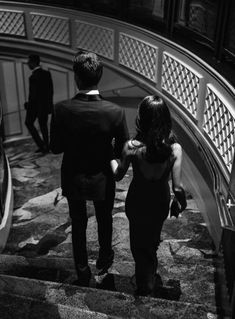 two people are walking down an escalator in black and white, one is holding the other's hand