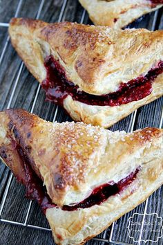 three pastries sitting on top of a wire rack next to each other, with jam in the middle