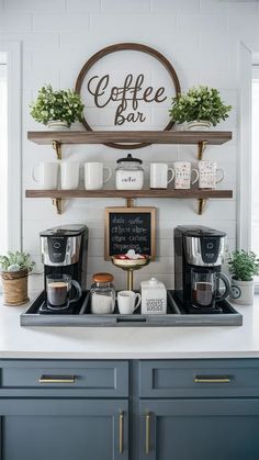 a coffee bar with cups and mugs on the shelf above it is decorated with greenery