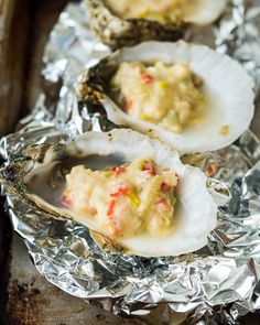 three oysters on tin foil with sauce and seasoning in the shell, ready to be eaten