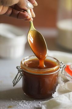 the spoon is full of caramel sauce on the table