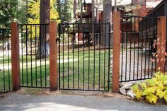 an iron fence with wooden posts in front of a house