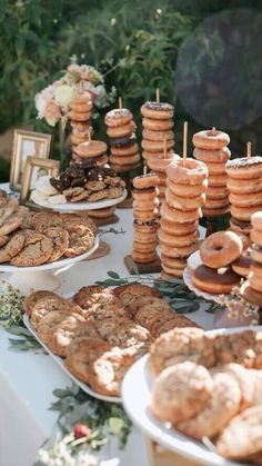 a table topped with lots of donuts covered in frosting next to other desserts