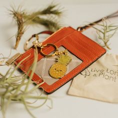 a pineapple keychain sitting on top of a card holder next to a plant