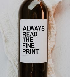 a bottle of wine sitting on top of a white blanket next to a black and white sign