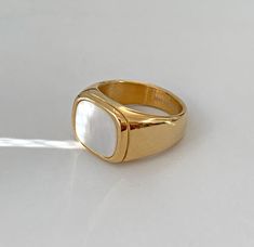 a gold ring with a white stone in the center on a white surface, it appears to be an oval shape