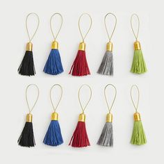 six tasselled ornaments in various colors and sizes, each with a gold - plated hook