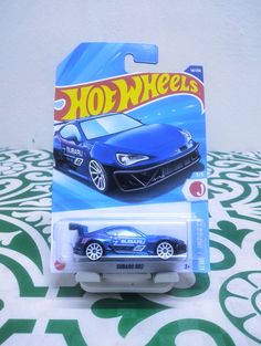 a hot wheels car is shown on a patterned tablecloth with a green and white background