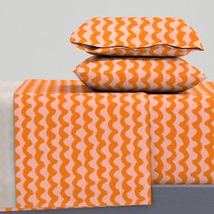 three pillows are stacked on top of each other in an orange and white pattern,