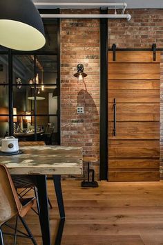 a wooden table sitting in front of a brick wall next to a black light fixture