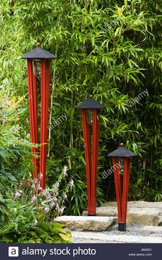 three red and black lamps in the middle of a garden