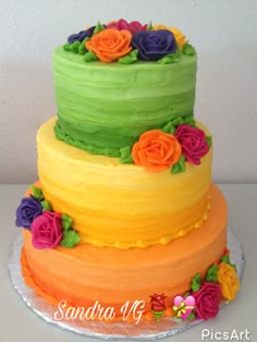 there is a multi layer cake with flowers on the top and bottom tiers that are green, yellow, orange, and pink