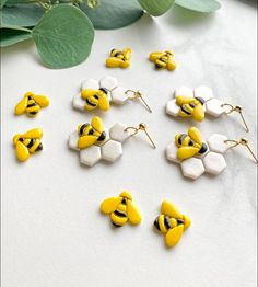 the yellow and white earrings are next to some green leafy leaves on a table