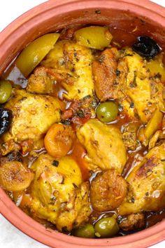 a bowl filled with chicken, olives and potatoes