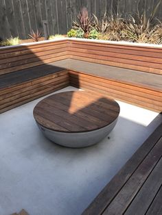 a wooden bench sitting on top of a cement floor next to a wooden wall and planter