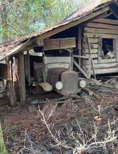 an old run down log cabin with rusted out cars parked in the dirt next to it