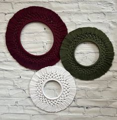 three circular crocheted doily hanging on a white brick wall next to each other