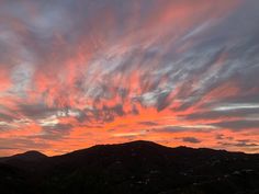 the sky is pink and orange as the sun sets in the distance over mountains with houses below