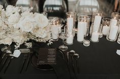 the table is set with white flowers, candles and silverware for an elegant wedding reception