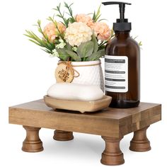 a soap dispenser with flowers in it sitting on a wooden table next to a bottle of lotion