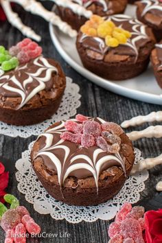 chocolate cookies with white frosting and candies on lace doily next to red roses