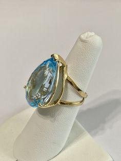 Stunning statement 14k yellow gold genuine blue topaz ring! This gorgeous ring contains a faceted pear cut genuine blue Topaz gemstone that weighs approximately 27.32 carats! The pear shaped gem is secured by 3 thick prongs. Incredible piece of fine jewelry featuring December birthstone! ERA - Modern, Estate METAL / MATERIAL - 14k yellow gold, 1 genuine Blue Topaz (approx. 27.32 cts) MARKINGS / HISTORY - Inside of ring is marked 14k CONDITION - Great vintage condition. SIZE / MEASUREMENTS - Size Fine Jewelry Yellow Gold Topaz Ring With Teardrop, Fine Jewelry Yellow Gold Topaz Teardrop Ring, Formal Yellow Gold Topaz Teardrop Ring, Pear-shaped Yellow Gold Topaz Ring, Gold Teardrop Topaz Ring For Formal Occasions, Fine Jewelry Blue Pear-shaped Topaz Ring, Blue Topaz Teardrop Ring Fine Jewelry, Fine Blue Topaz Ring Pear-shaped, Anniversary Yellow Gold Teardrop Topaz Ring