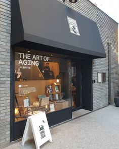 the front of a store with an open window and sign in front of it that says the art of aging