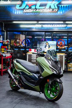 a green and black scooter parked in front of a shop with neon lights