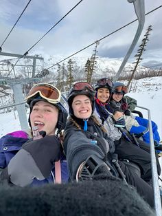 four people riding on a ski lift in the snow