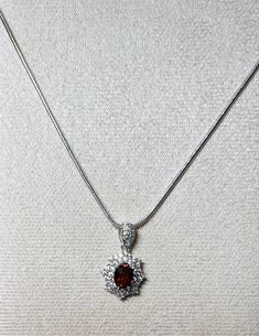 "Gemstone: genuine natural oval cut spessartite garnet Size: 7mm x 5mm Weight: .64ct approx Accent stones: round cut white cubic zirconia Total length including bail: 3/4\" Total width: 1/2\" Metal: .925 stamped sterling silver, rhodium plated  Chain: 18\" snake chain, 1.5mm wide, with lobster clasp, rhodium plated  Total weight: 2.3g" Elegant Oval Garnet Necklace, Oval Garnet Necklaces For Anniversary, Oval Garnet Necklace For Anniversary, Elegant Garnet Jewelry With Round Stone, Elegant Garnet Round Jewelry, Formal Oval Garnet Pendant Jewelry, Elegant Garnet Jewelry, Round Garnet Gemstone Necklaces, Oval Cubic Zirconia Necklace With Gemstone Accents