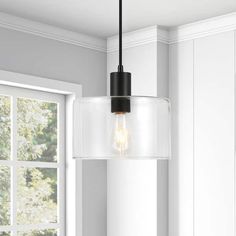 a light fixture hanging from the ceiling in a room with white walls and windows behind it