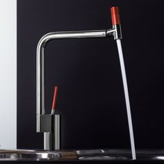 a kitchen faucet with red handles and water running from the faucet