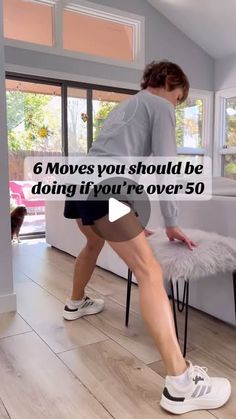 a woman standing on top of a stool in a living room next to a dog